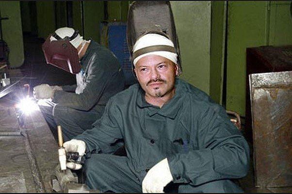 Работник в сварке в мастерской, в защитной каске и перчатках