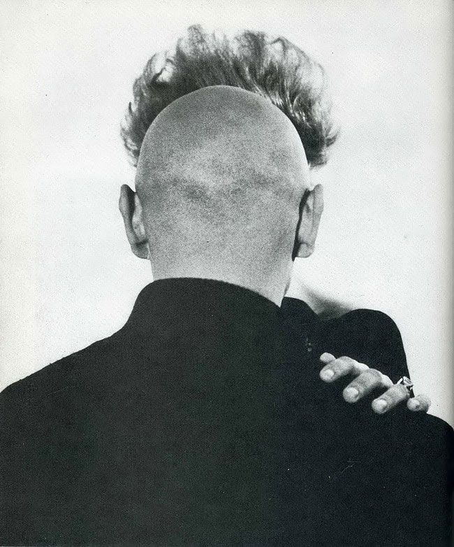 Черно-белое фото: человек с оголённой макушкой обнимает другого человека спиной к камере