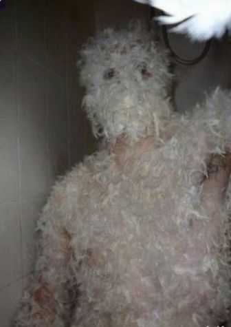 Человек в белом пушистом костюме из перьев в темной подсветке.