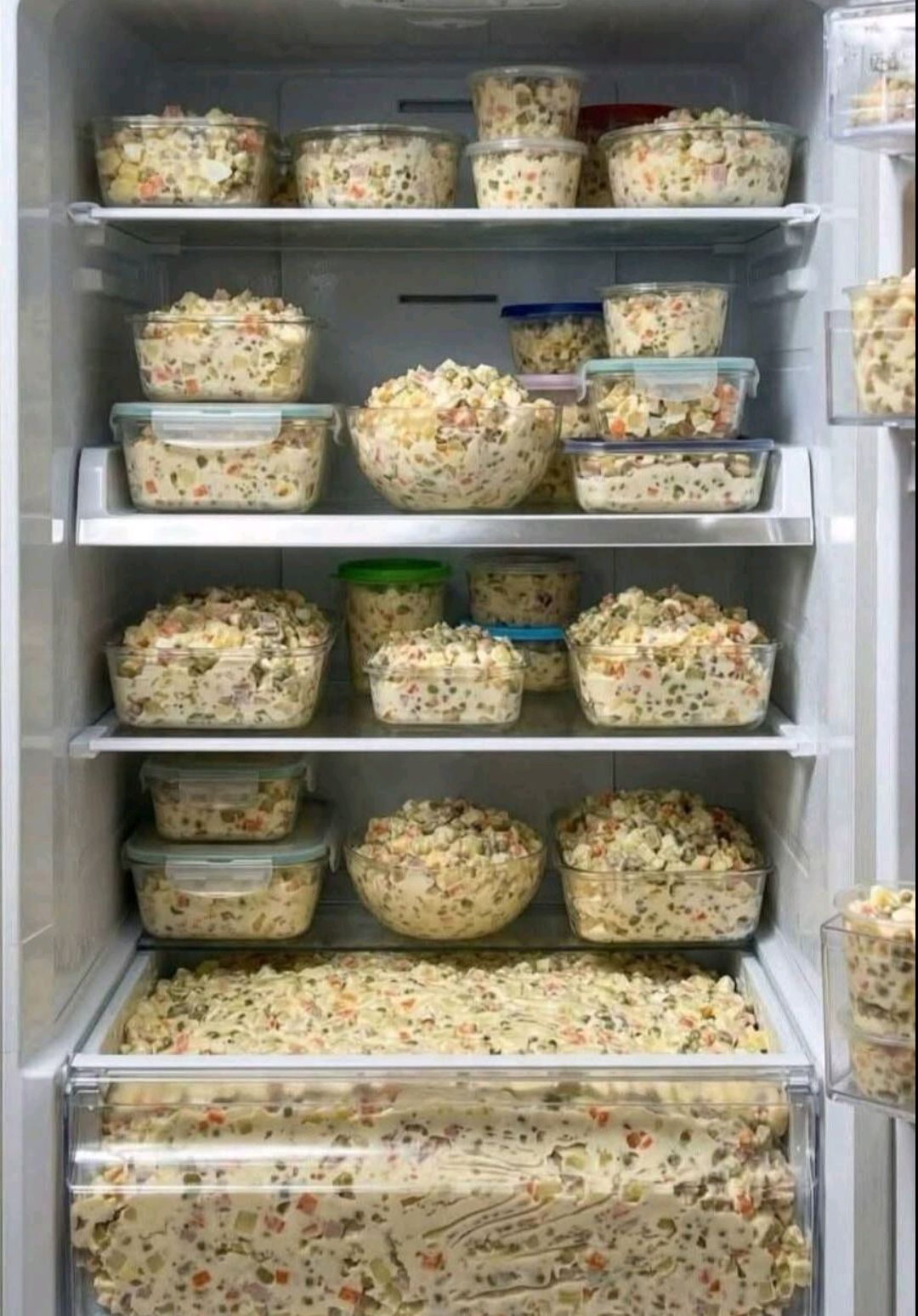 Много пластиковых контейнеров с едой на полках холодильника