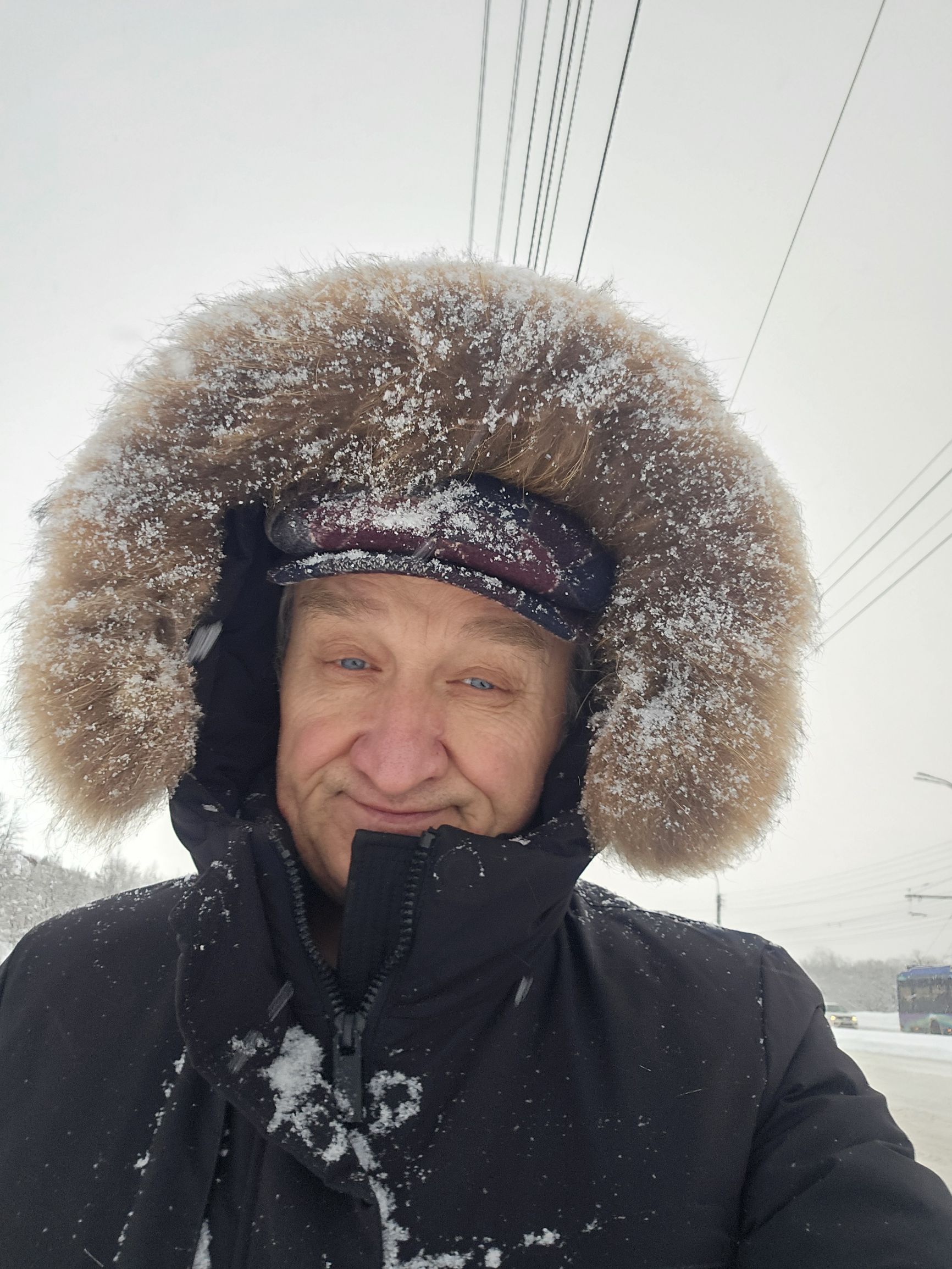 Мужчина на улице в снегу в тёплом шубе с меховым капюшоном