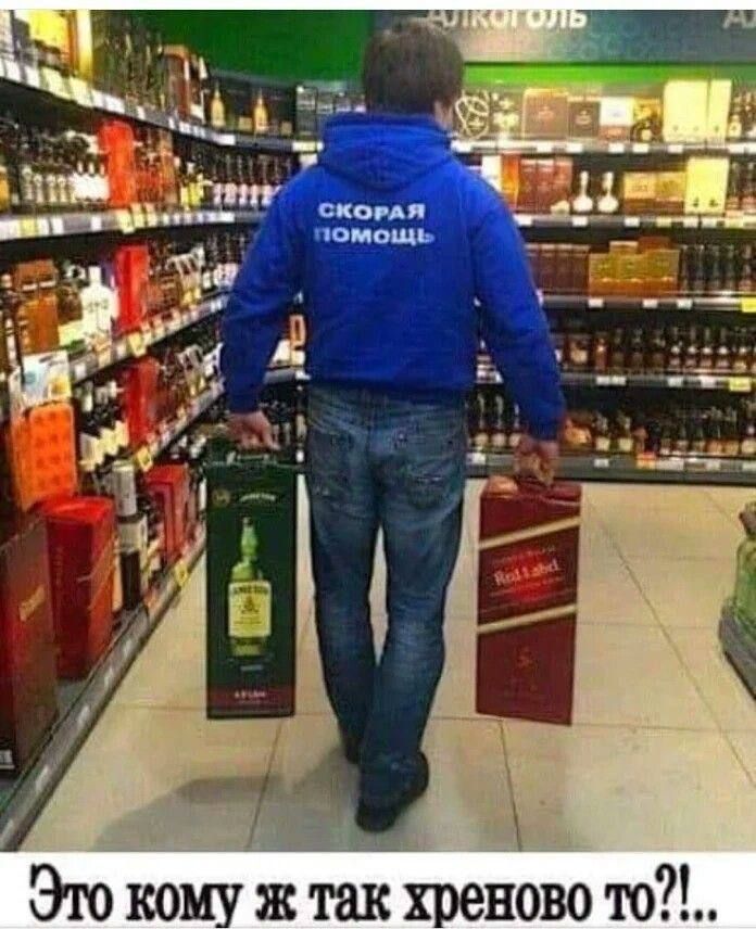 На куртке написано 'СКОРАЯ ПОМОЩЬ'. На кадре мужчина в синей куртке несёт две коробки в магазине; снизу подпись: 'Это кому же так хреново то?!'.