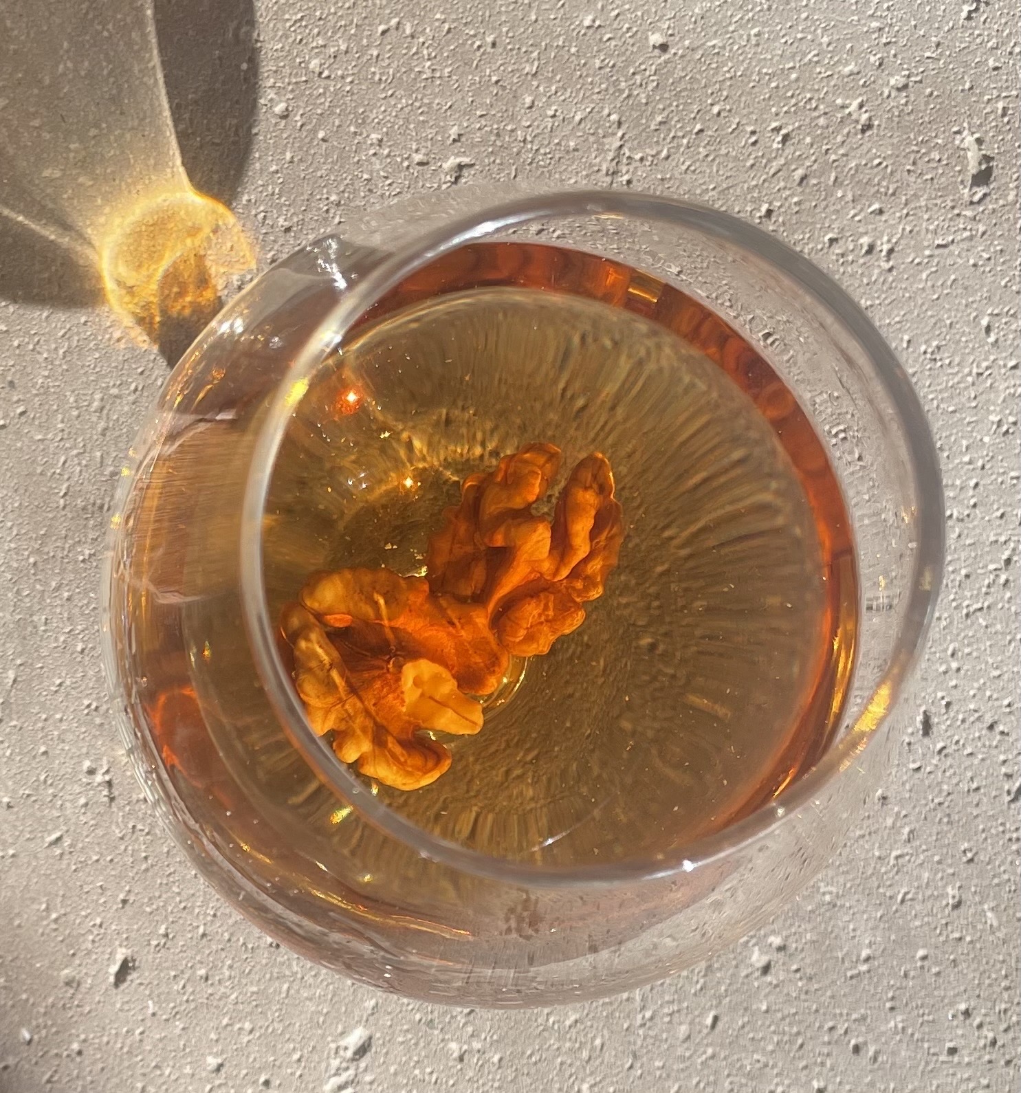 Бокал напитка с орехами внутри на светлой поверхности