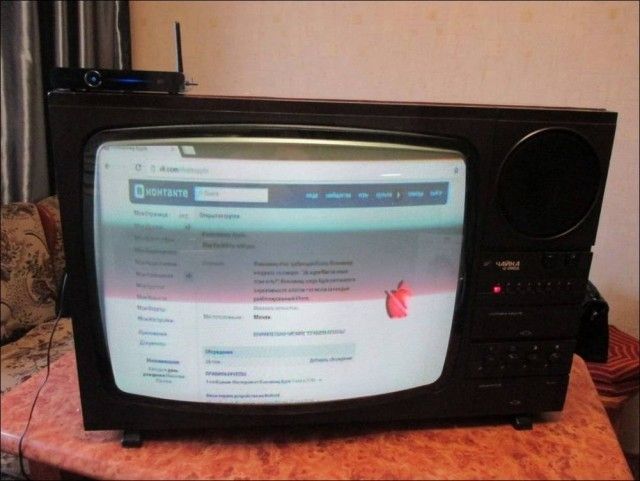 Старый телевизор с антенной на столе, на экране открыта веб-страница (русский сайт).