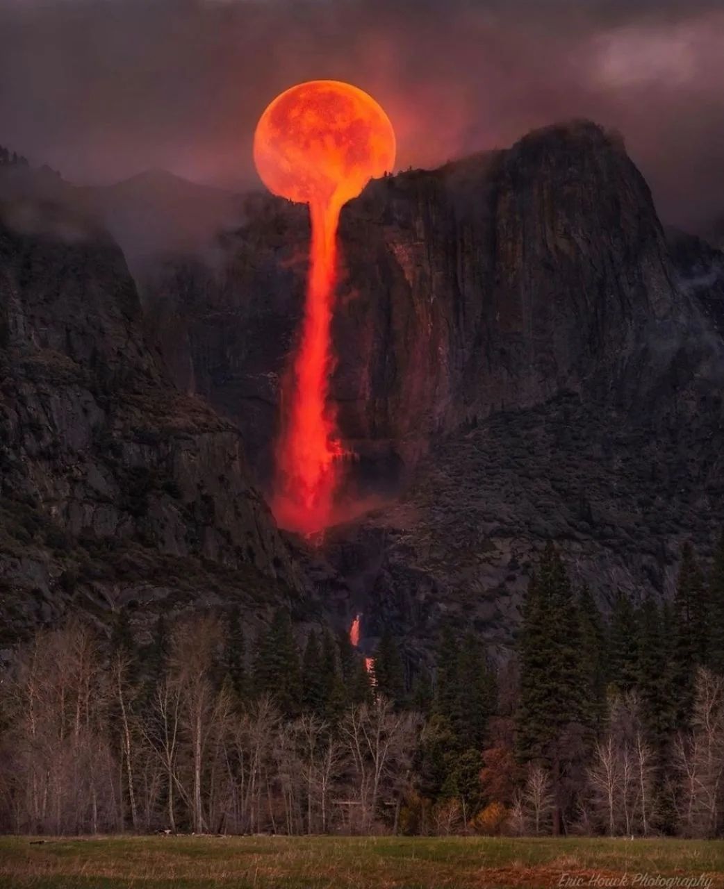 Сюрреалистический красный столб лавы между горами и деревьями