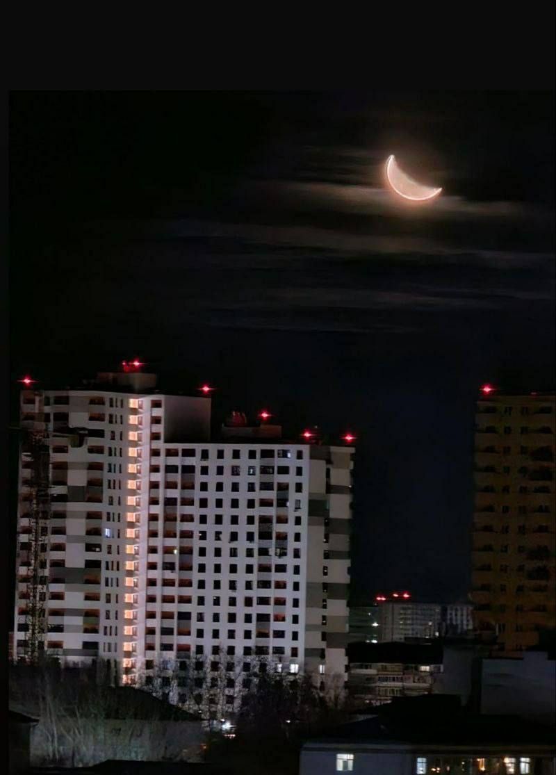 ночной город с полумесяцем над высотками