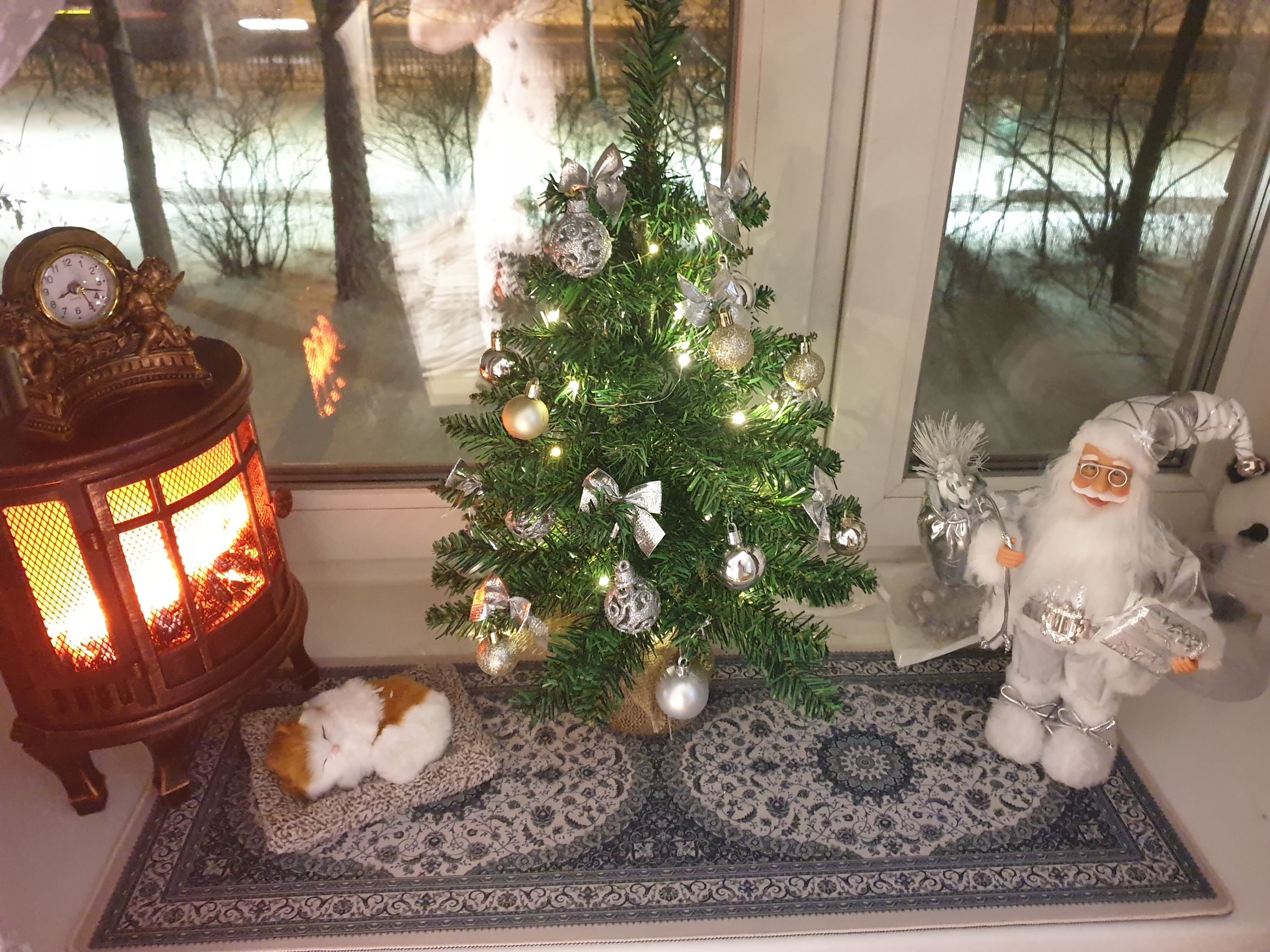 Новогодняя сцена: маленькая ёлка, камин, Санта и кот на подоконнике.
