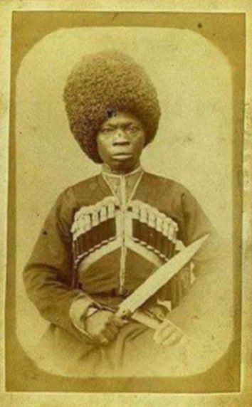 Черно-белое старое фото мужчины в военной форме с саблей и меховой шапкой