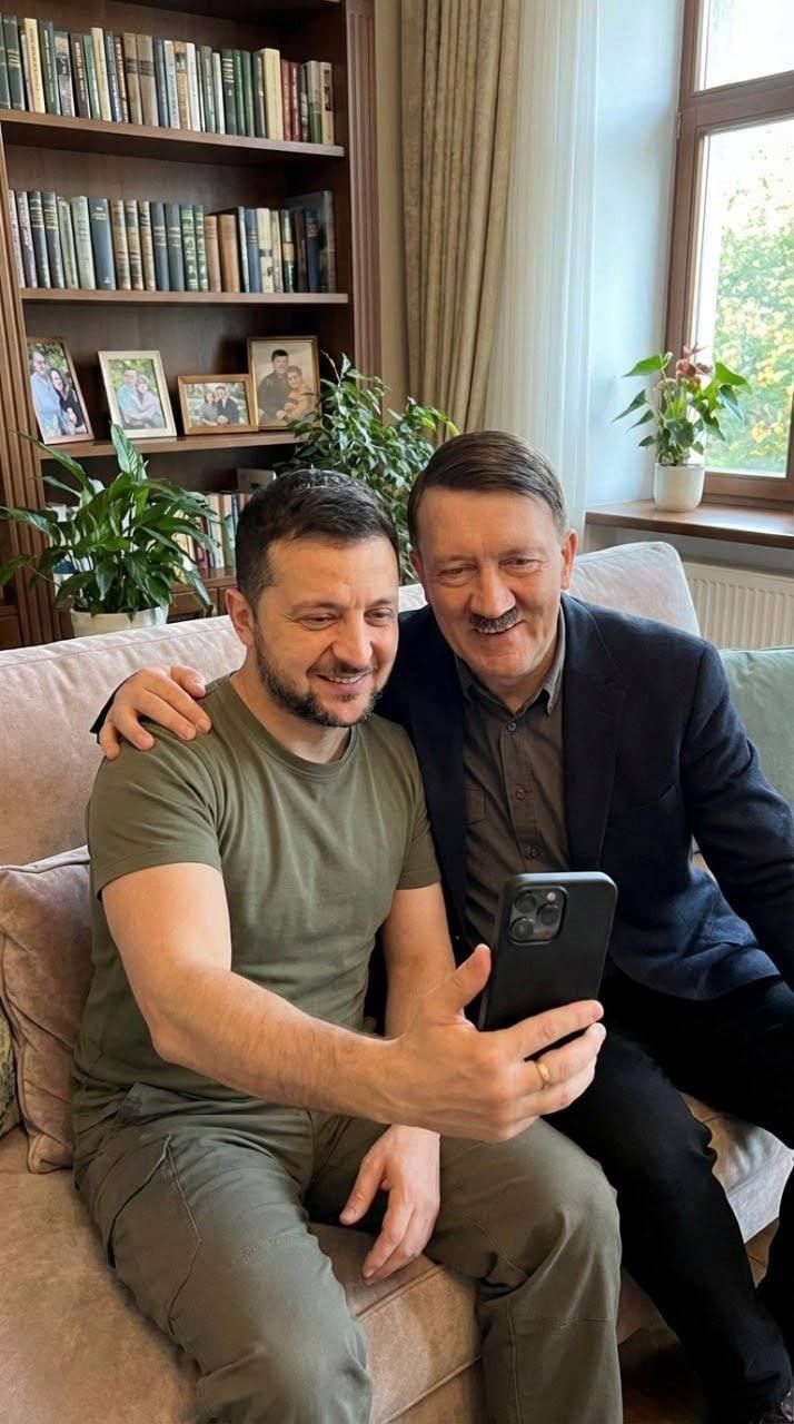 Два мужчины сидят на диване и делают селфи в доме.