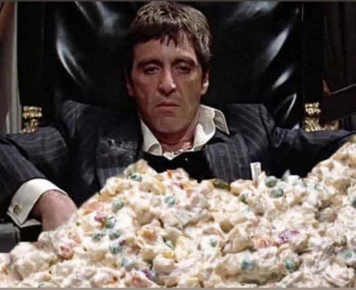 Мужчина в костюме за огромной кучей салата/картофельного пюре на столе