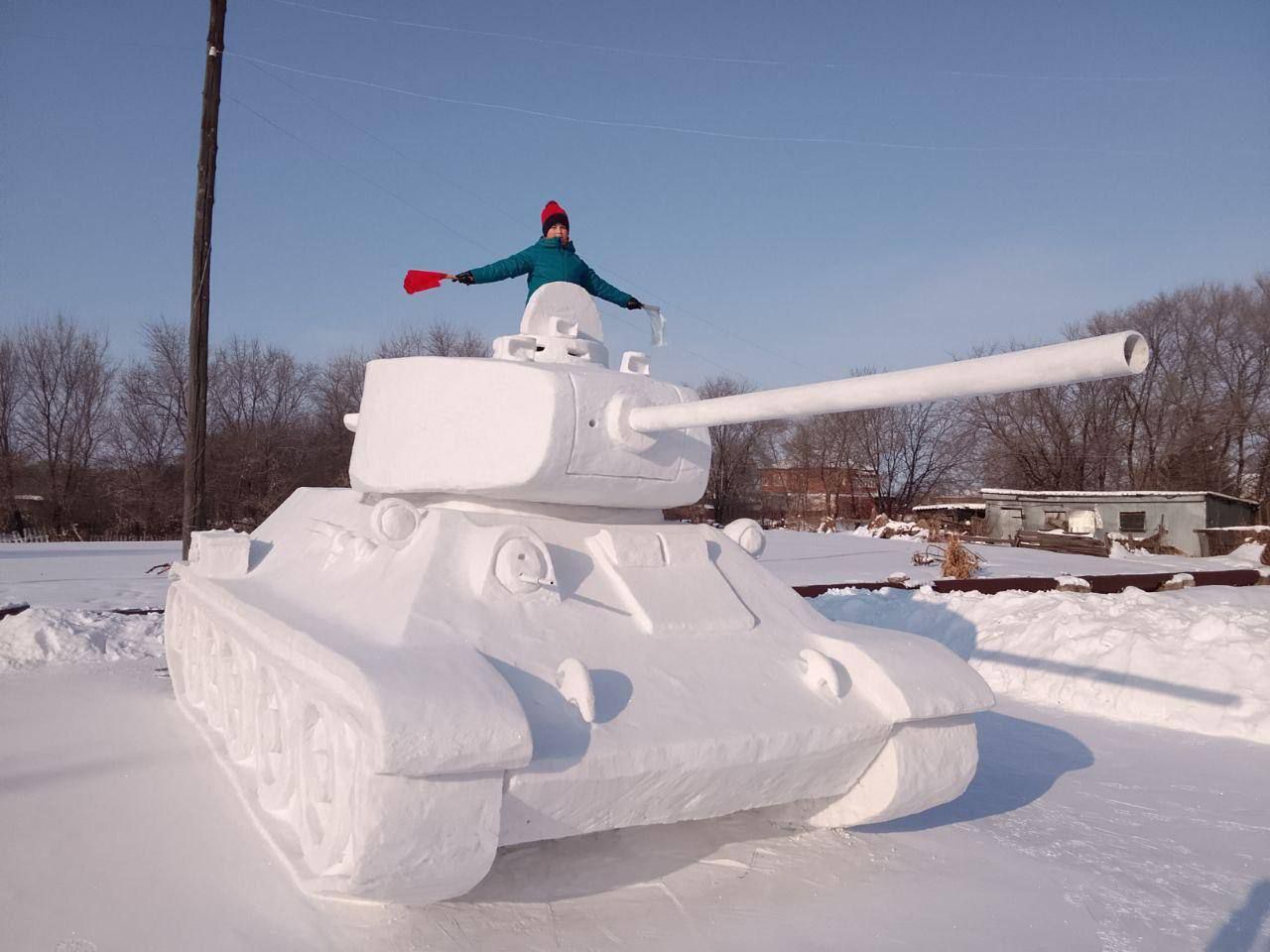 Снеговой танк с человеком на башне в заснеженном поле