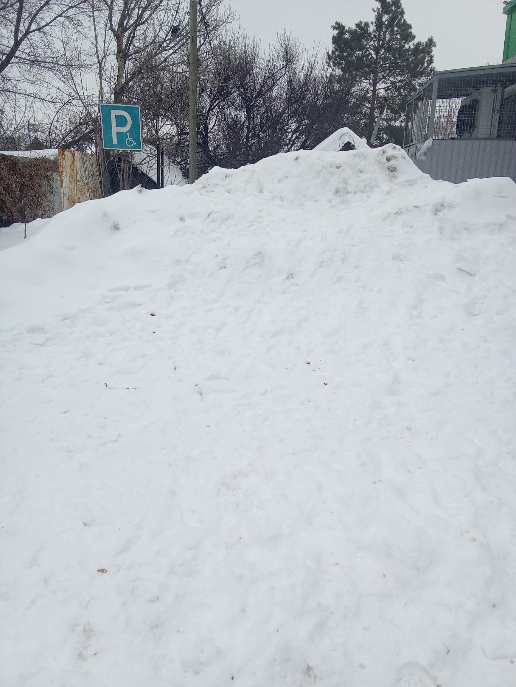 Сугробы у парковки, гололед и снегопад на улице