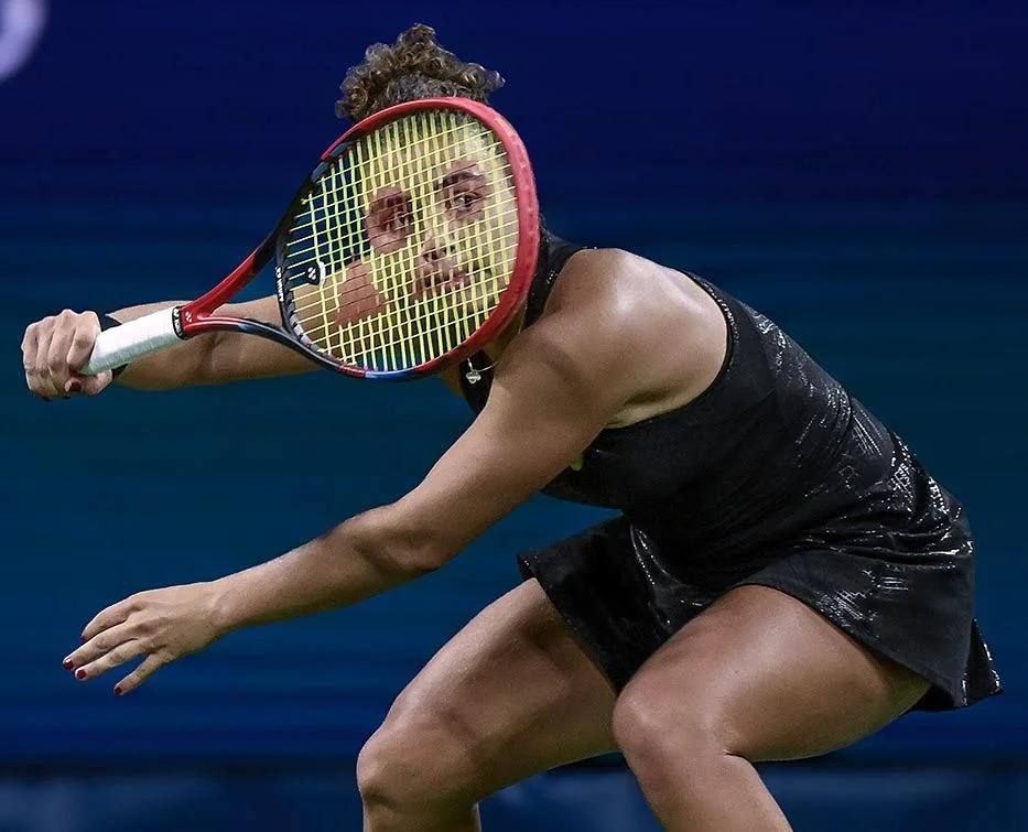 Спортсменка в черном платье держит ракетку в движении на корте.