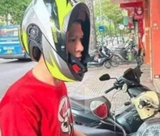 Парень в мотокаске стоит рядом с мотоциклами на улице.