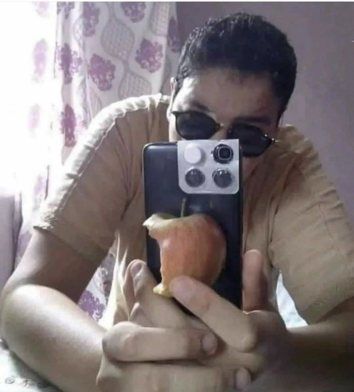 Мужчина в очках делает селфи с яблоком на телефонном чехле.