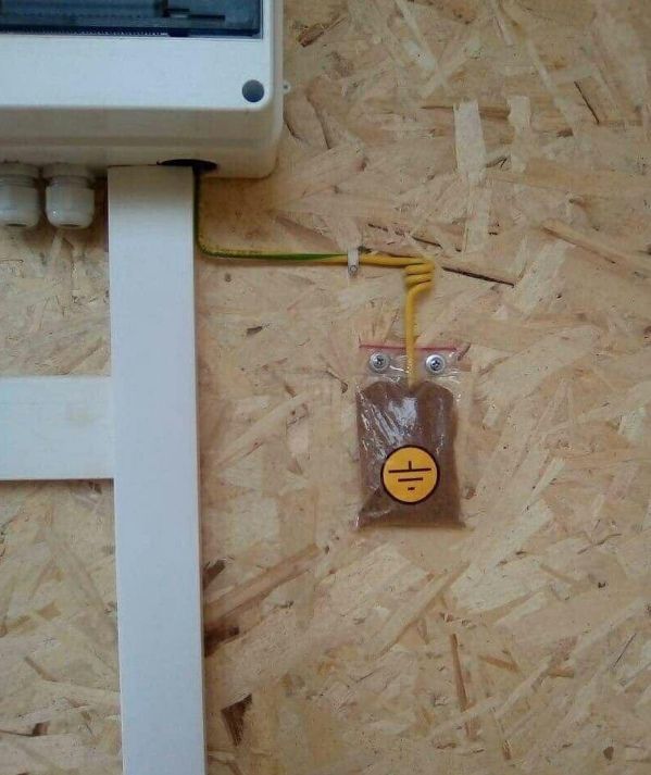 Открытые провода и запаянный пакет на деревянной стенке, выглядит как опасная электрика.