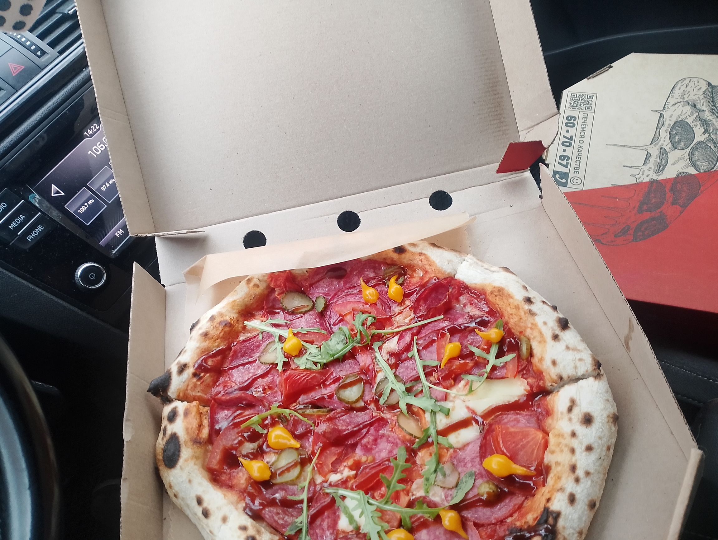 Пицца в коробке на переднем сиденье автомобиля