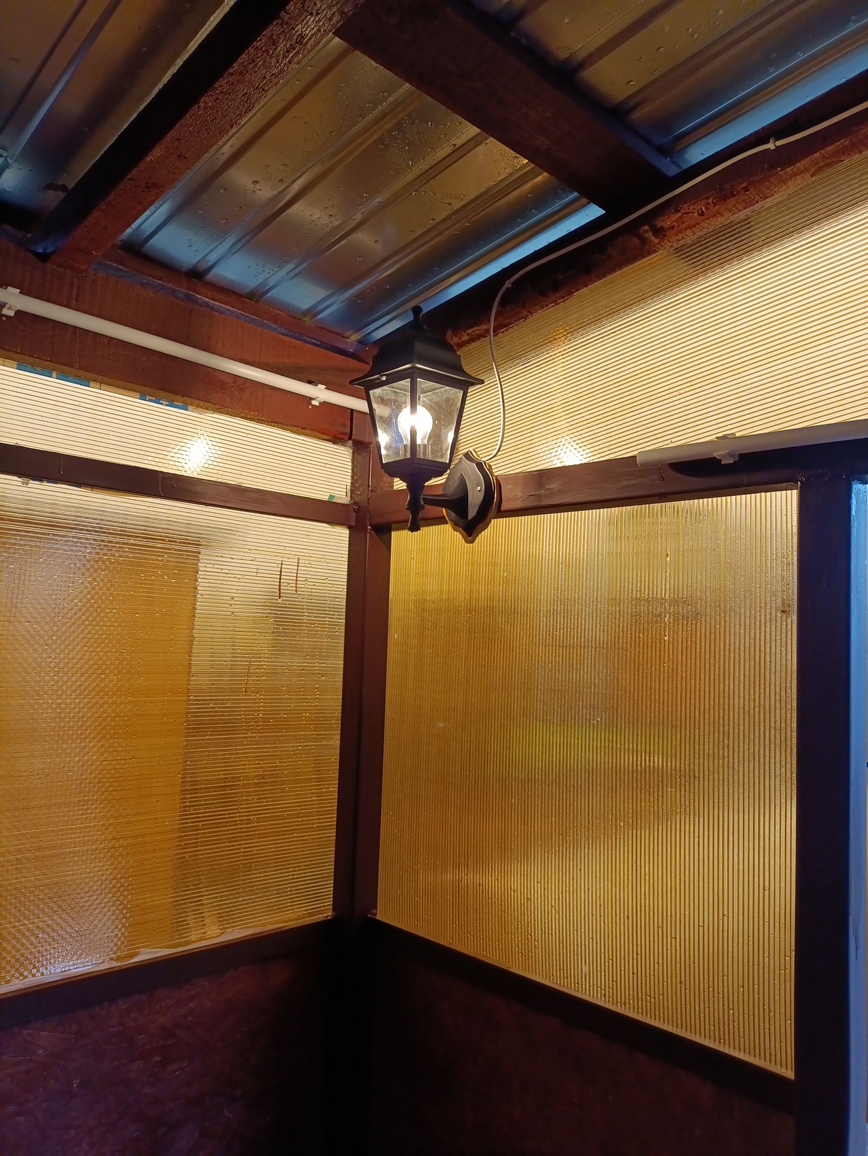 Уютная веранда с желтыми стеклянными стенами и подвесным фонарём