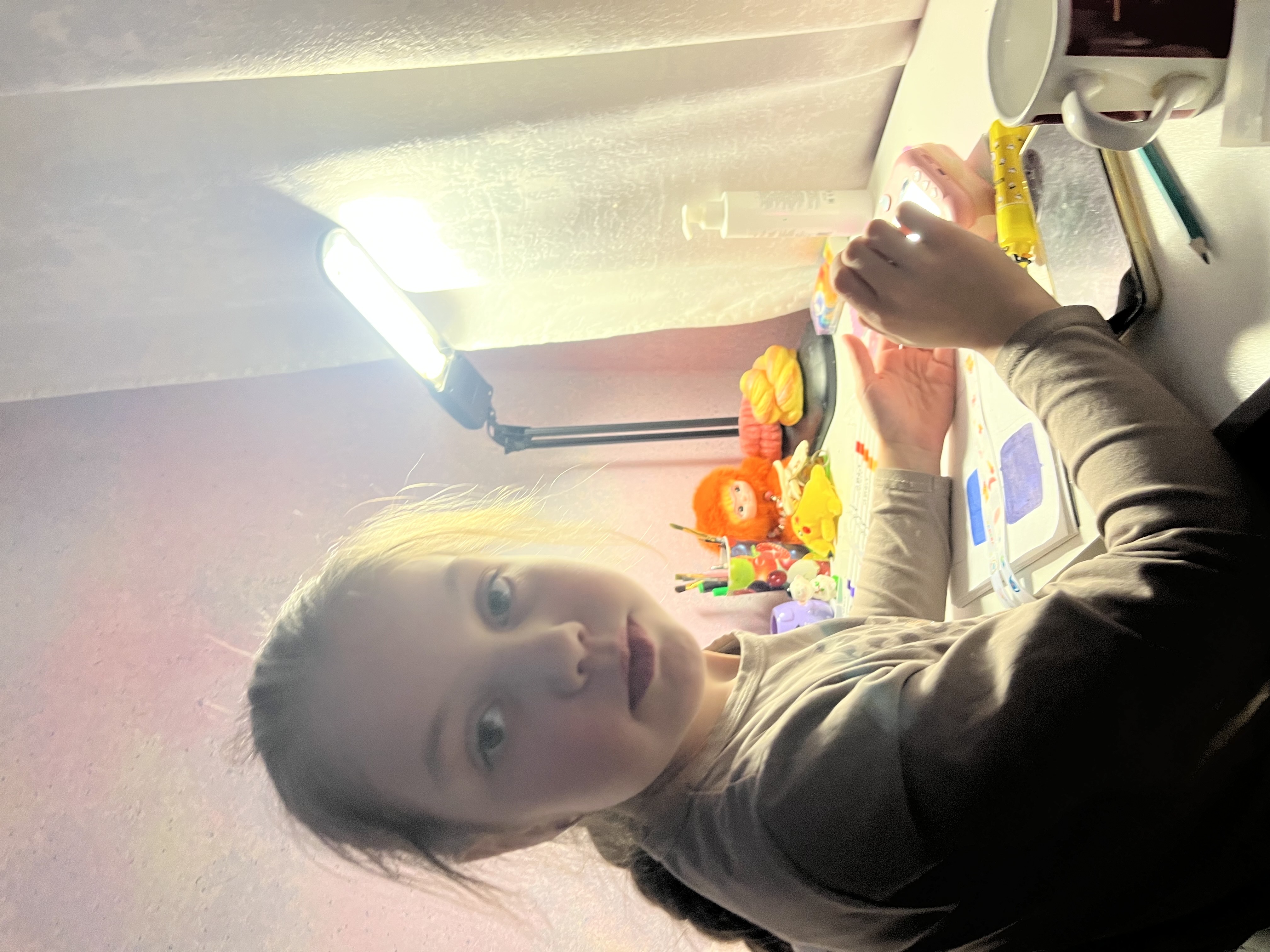 ребенок за столом с игрушками и светом лампы