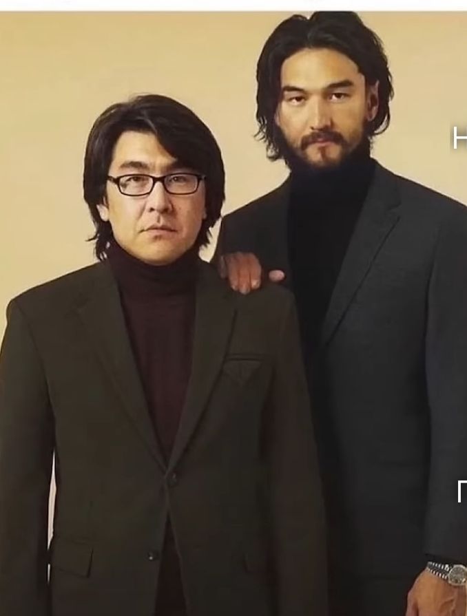 Две мужчины в деловых костюмах, один держит руку на плече другого.