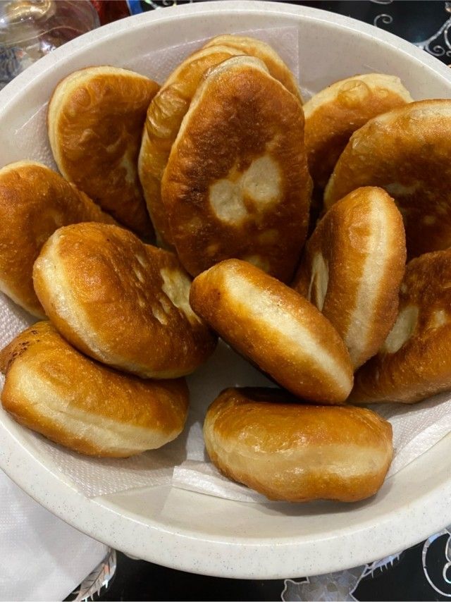 Круглые жареные мини-булочки/пончики в белой пластиковой тарелке