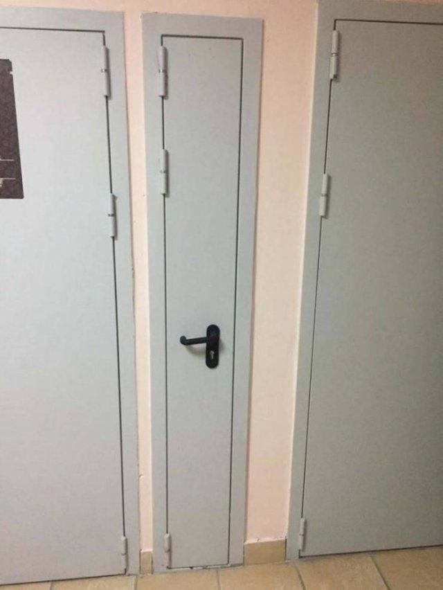В коридоре ряд серых дверей, центральная узкая дверь с ручкой слева.