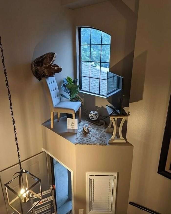 Увлекательный двухуровневый интерьер с диваном, телевизором и головой динозавра.