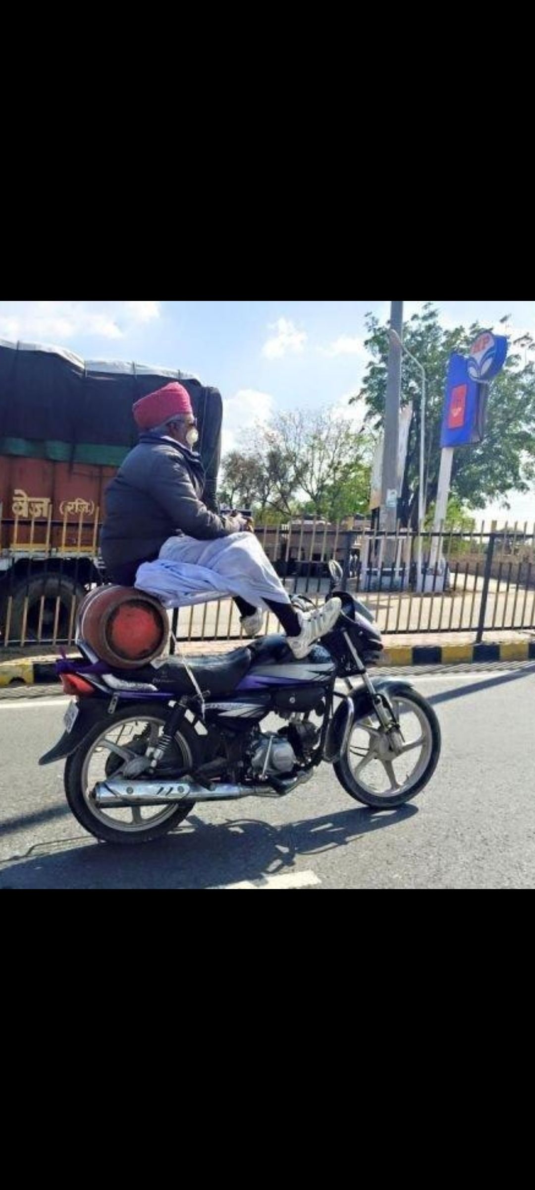 Мужчина едет на мотоцикле с багажом на колесах через городскую дорогу