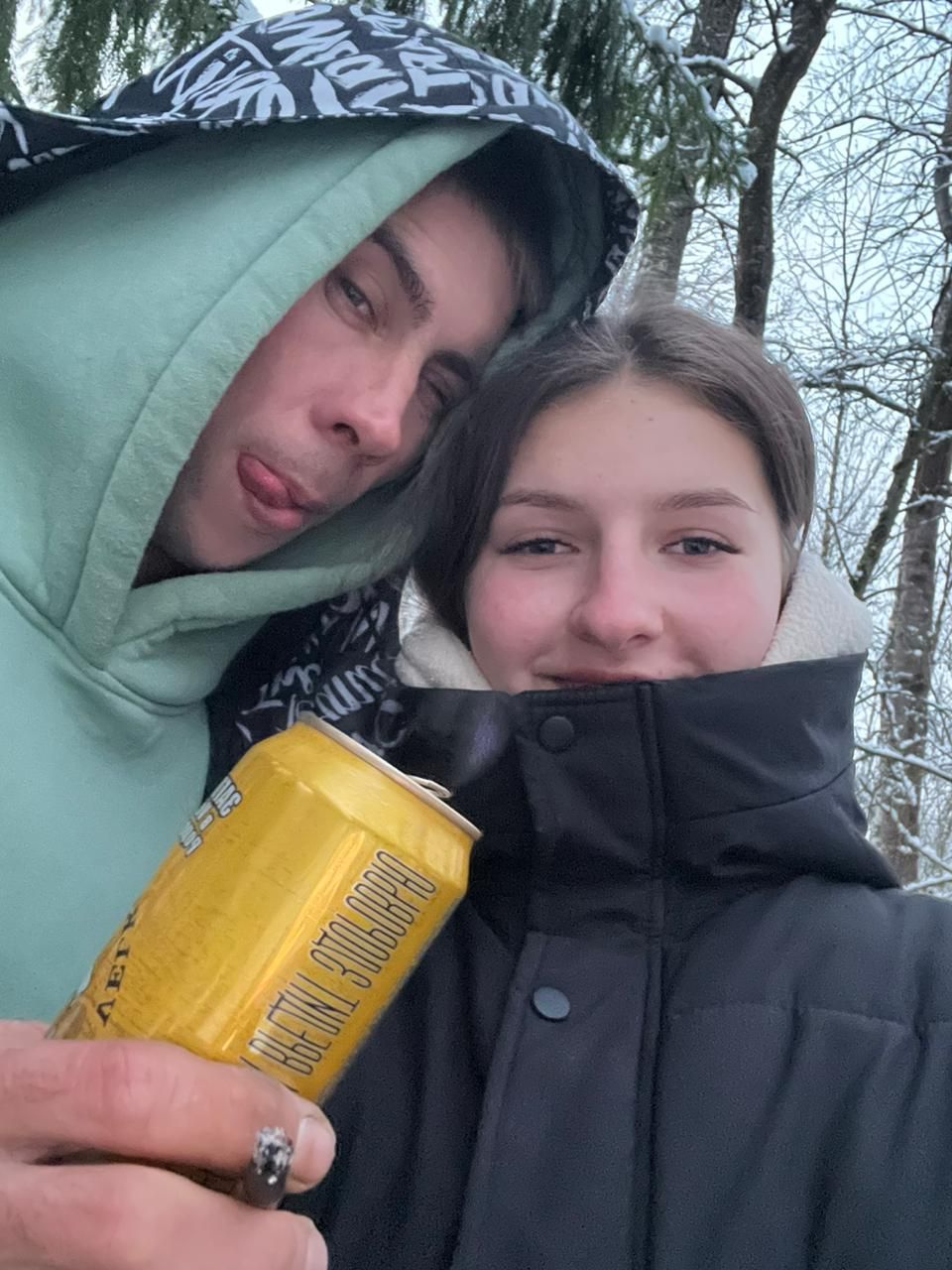 Пара в зимнем виде снимается на улице, держит жёлтую банку