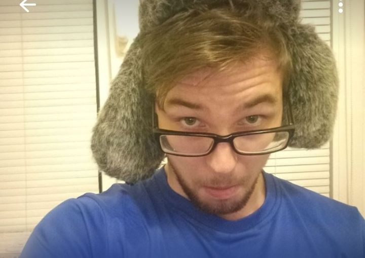 Мужчина в синей футболке в ушанке с ушами делает селфи