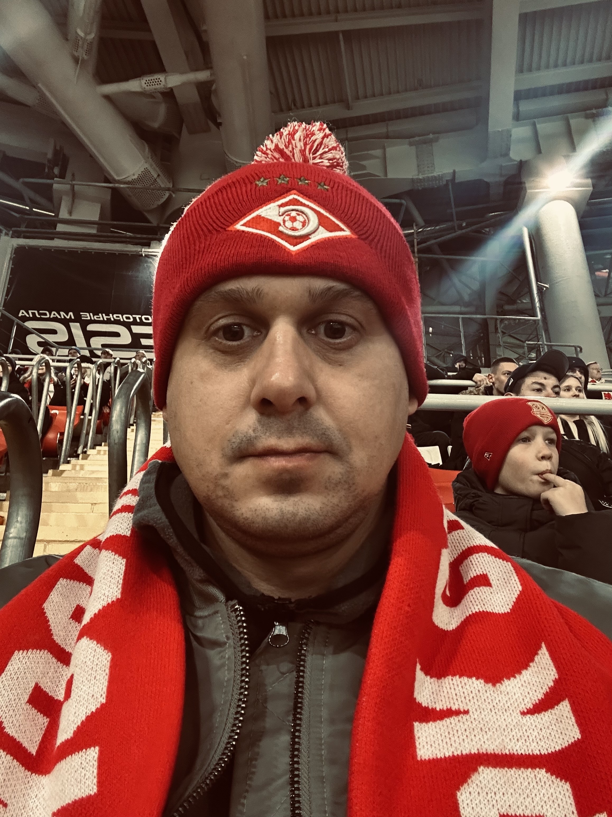 Мужчина в красной шапке и шарфе болельщика в спортивном стадионе