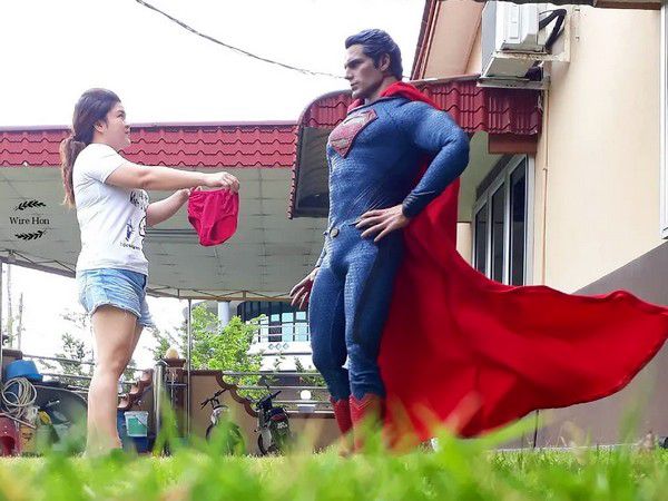 Девушка дарит Красному Супермену плащ во дворе