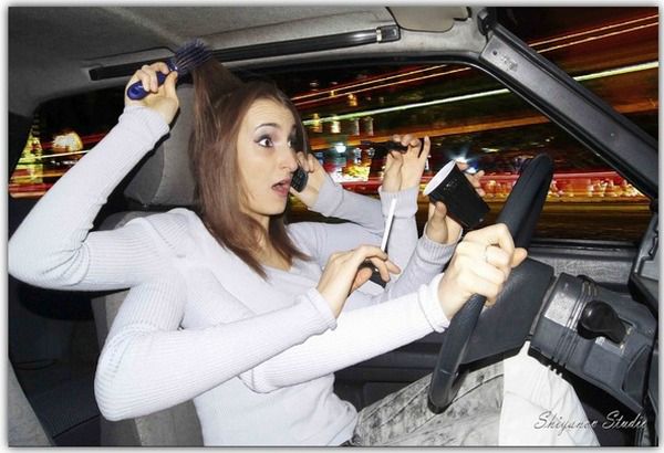 Женщина за рулём автомобиля пытается делать макияж и прическу.