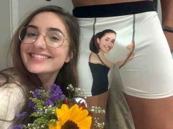 Девушка улыбается и держит букет; на шортах изображение другой женщины.