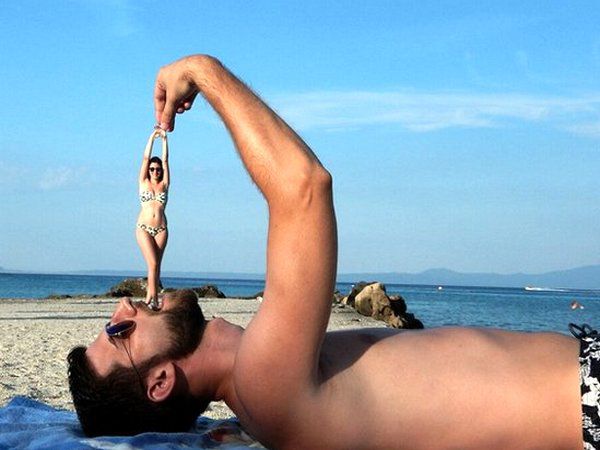 Человек на пляже держит миниатюрную куклу над своим ртом, создавая забавный эффект.