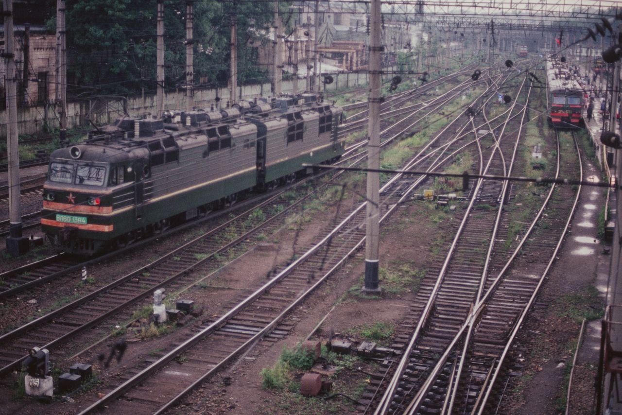 Поезда на железнодорожных путях, перспектива нескольких линий и станционных опор.