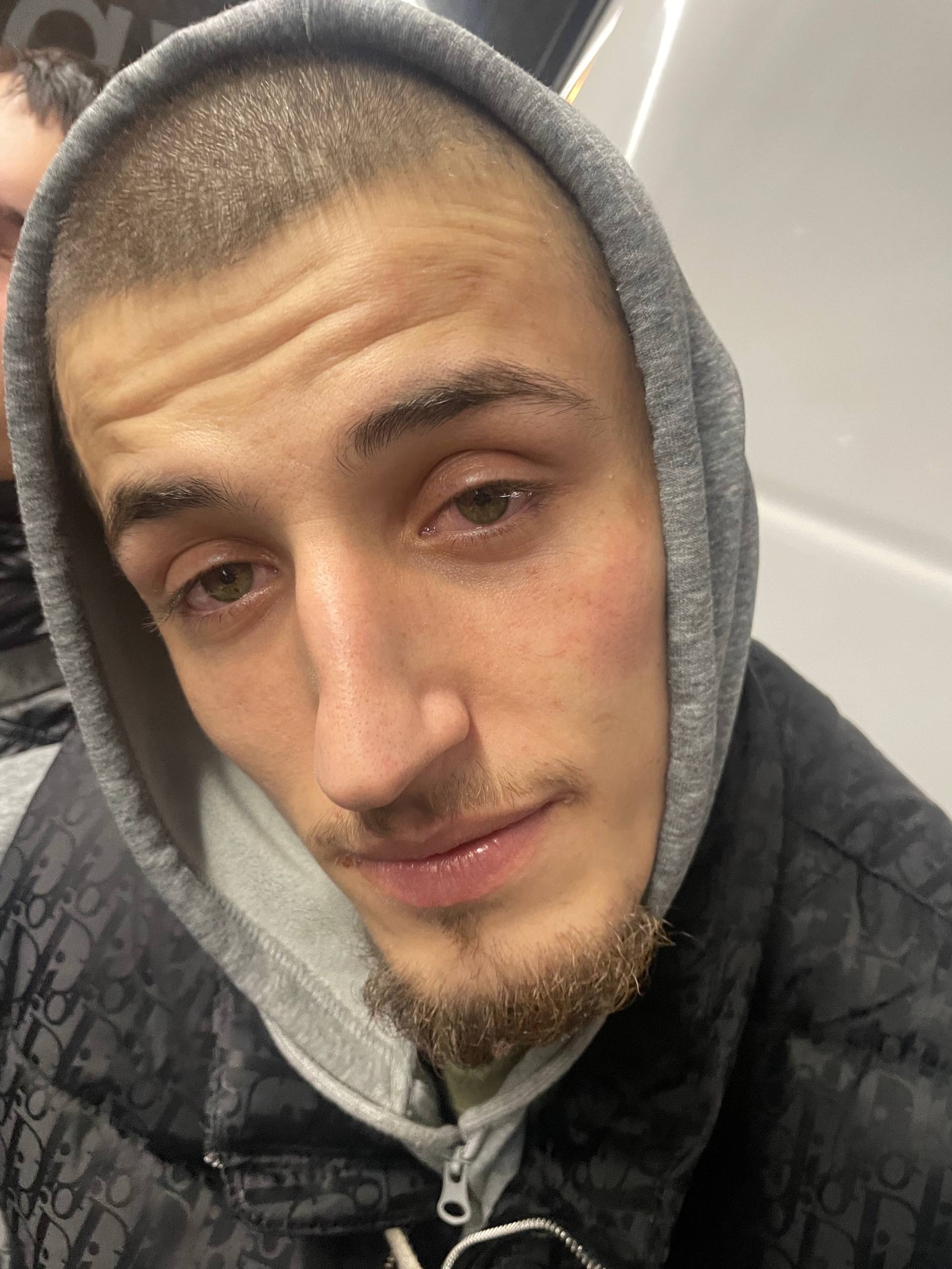 Близкий портрет парня в сером худи на фоне поезда