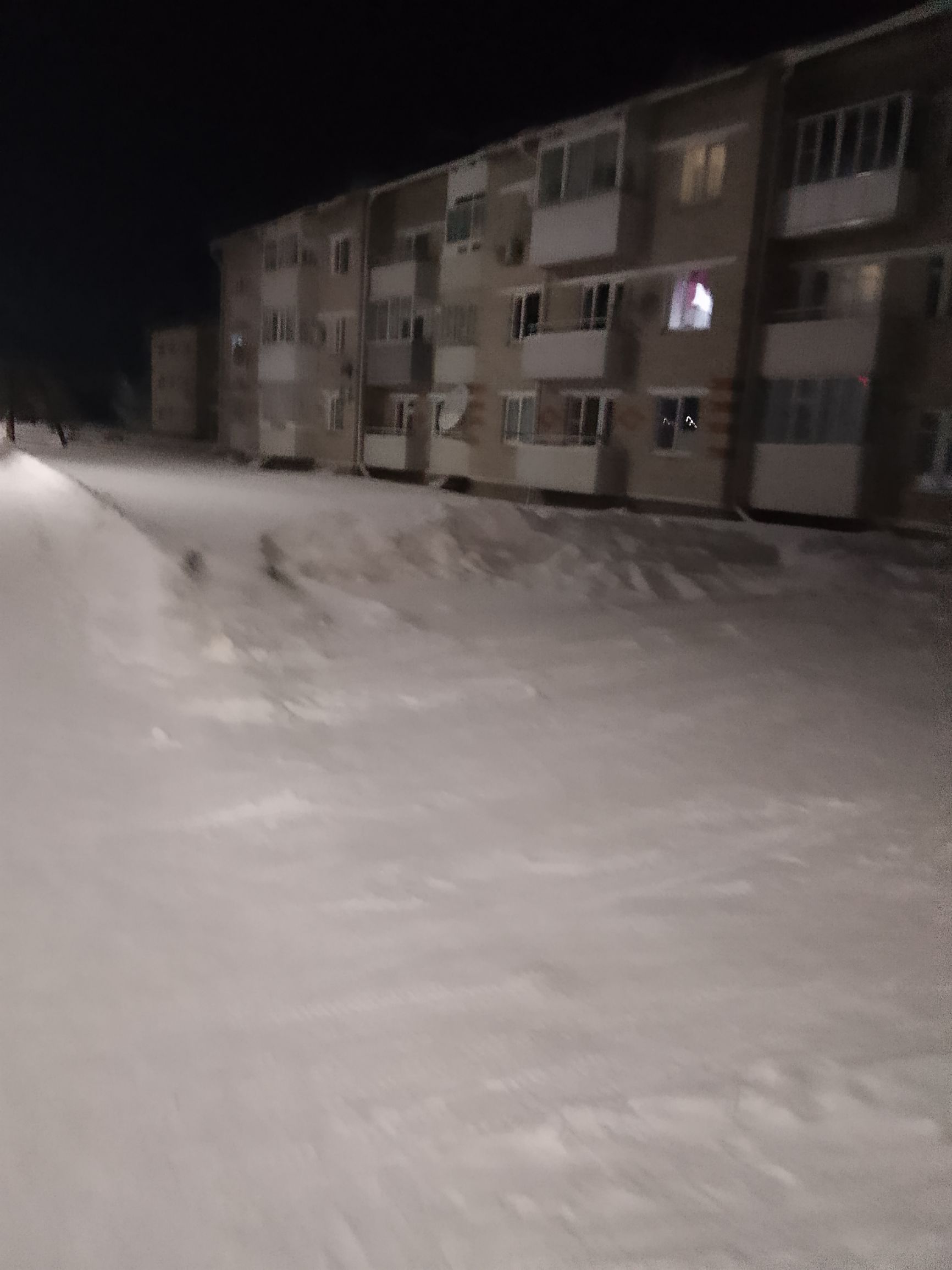 ночной снимок двора многоквартирного дома в снегу