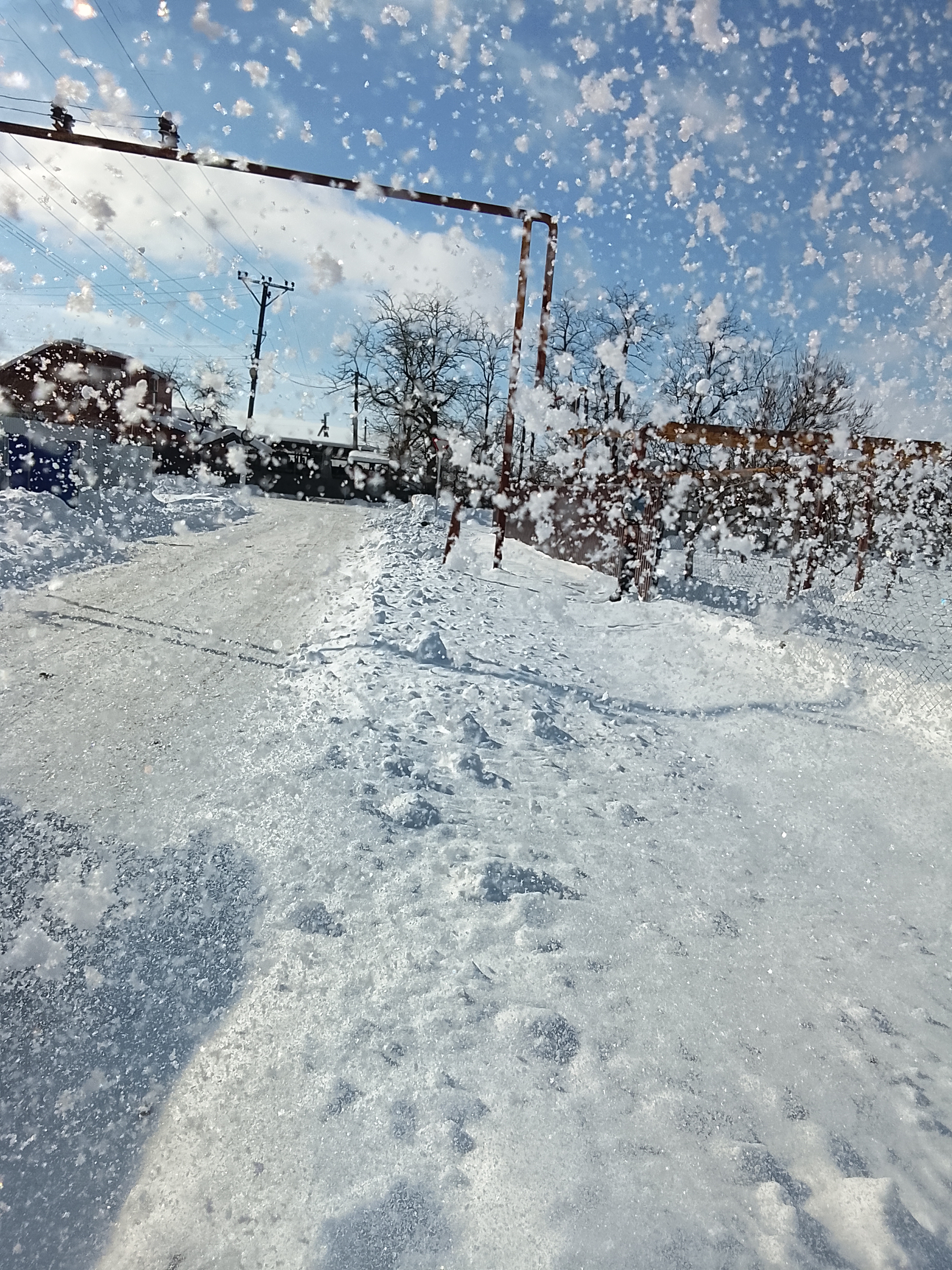 Зимняя сцена на снежной улице, заснеженный спортплощадкой воротами и падающими хлопьями снега.