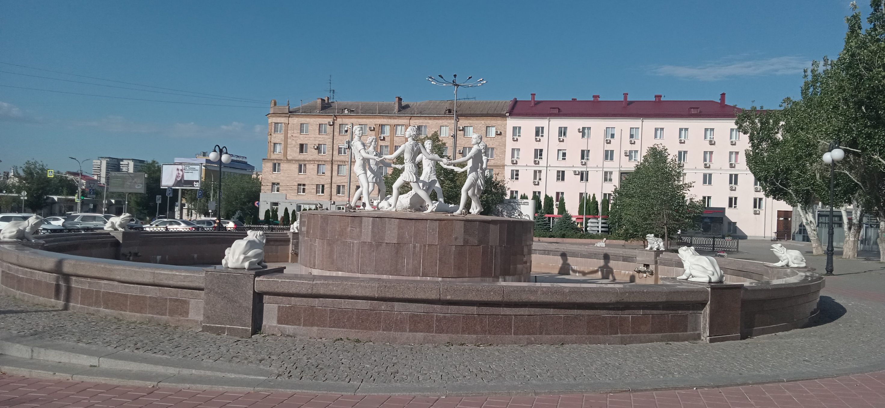 Фонтан с барельефами и скульптурами на площади, позади здания.