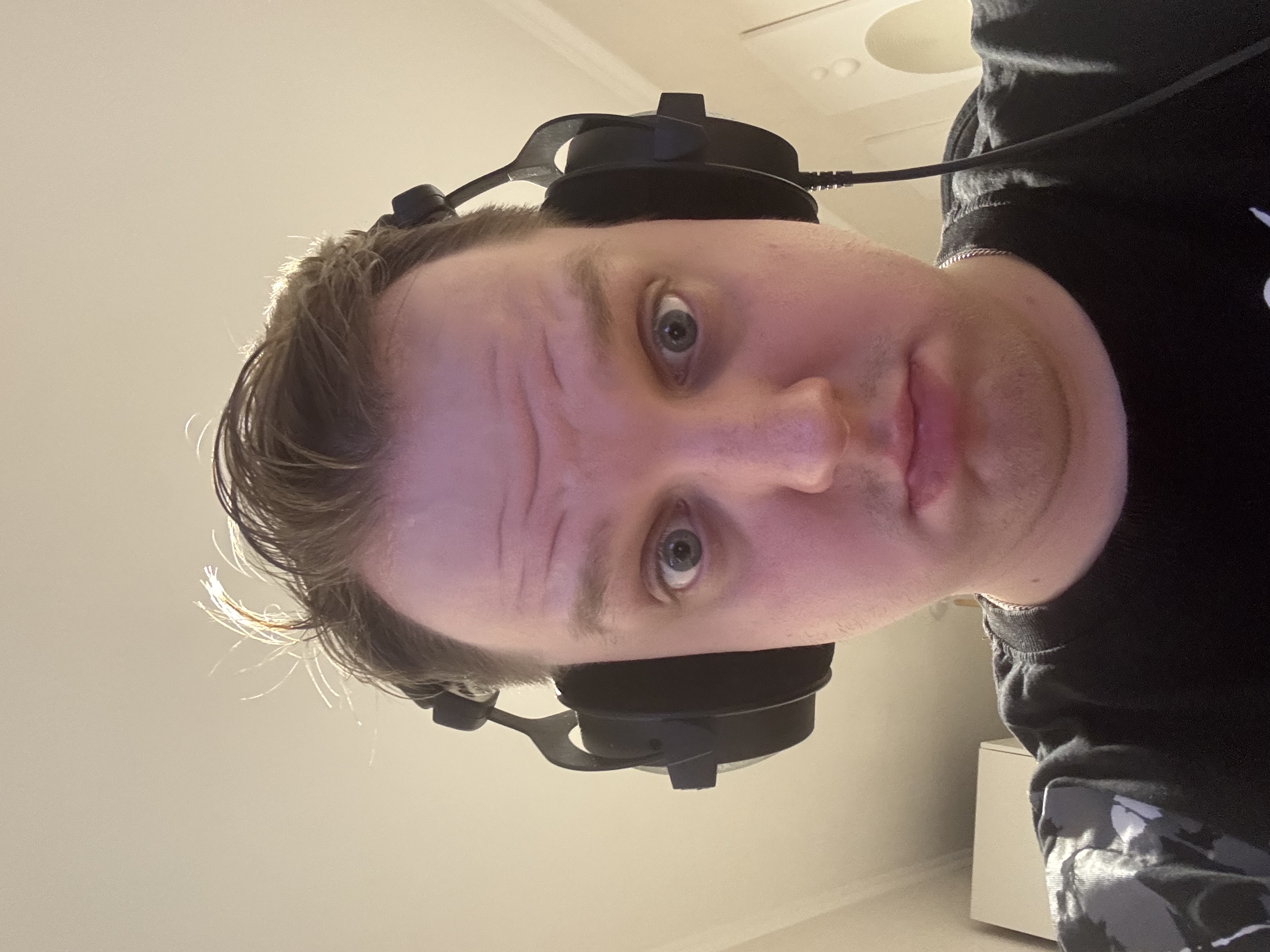 Человек в наушниках смотрит в камеру, кадр повернут вверх ногами