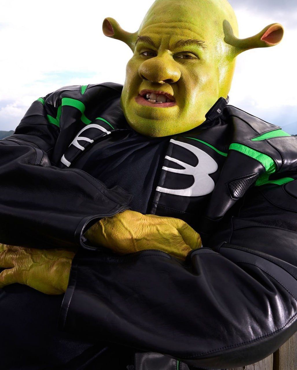 Человек в костюме зелёного монстра, похожего на Шрека, крупный план лица.