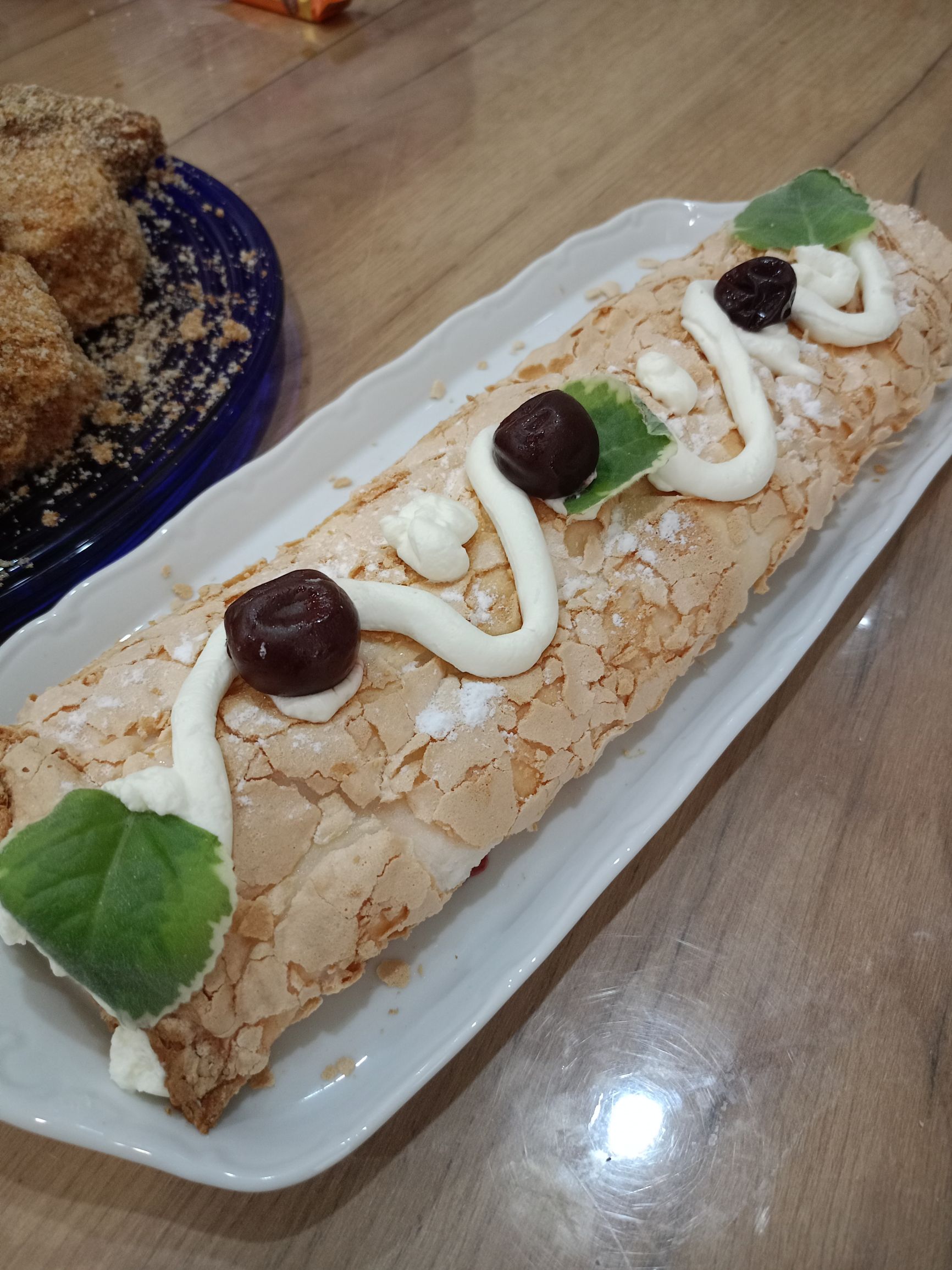 Рулет с миндальной коркой, кремом и вишнями на тарелке