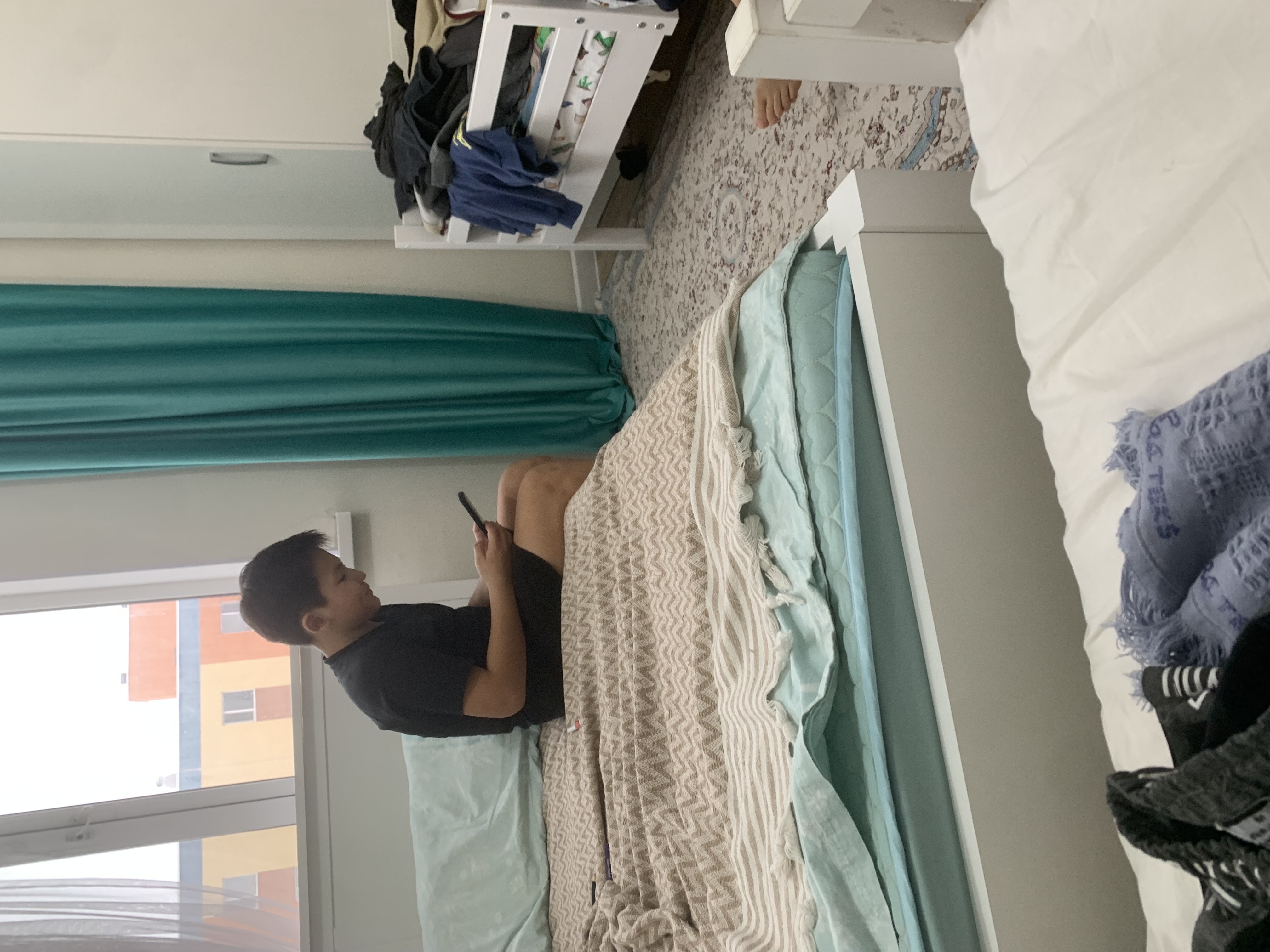 Комната с мужчиной на кровати, смотрит в телефон