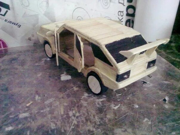 Деревянная игрушечная машина с открытыми дверями и багажником.