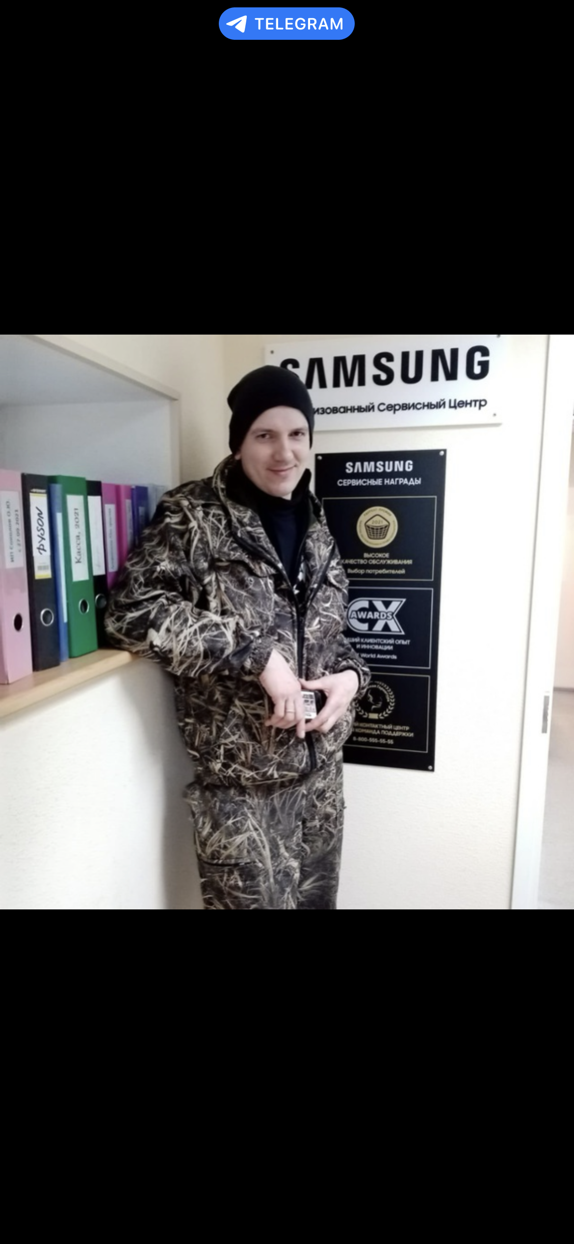 SAMSUNG Авторизованный Сервисный Центр SAMSUNG СЕРВИСНЫЕ НАГРАДЫ ВЫСОКОЕ КАЧЕСТВО ОБСЛУЖИВАНИЯ Выбор потребителей CX AWARDS ЛУЧШИЙ КЛИЕНТСКИЙ ОПЫТ И ИННОВАЦИИ World Awards КОНТАКТНЫЙ ЦЕНТР КОМАНДА ПОДДЕРЖКИ DYSON Касса, 2021. Мужчина в камуфляжной одежде и шапке стоит в сервисном центре Samsung.
