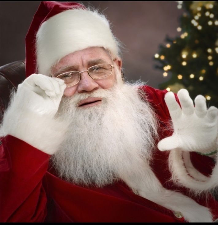 Санта-Клаус в праздничном наряде машет рукой.