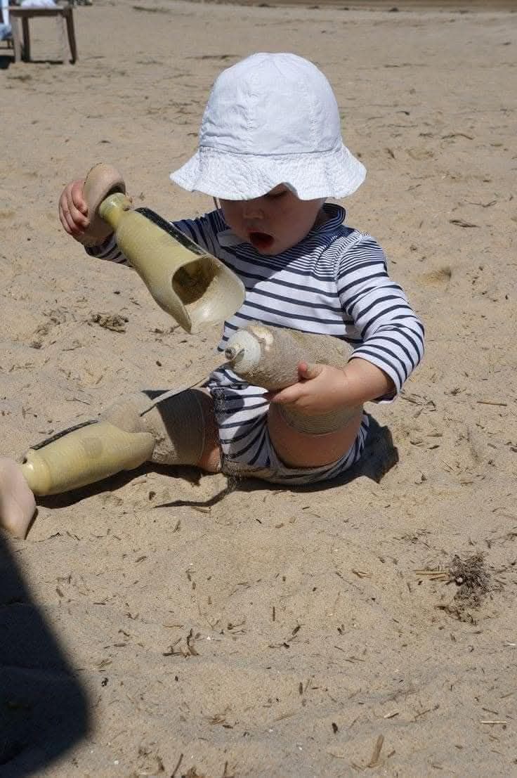мальчик на пляже играет с песочными игрушками