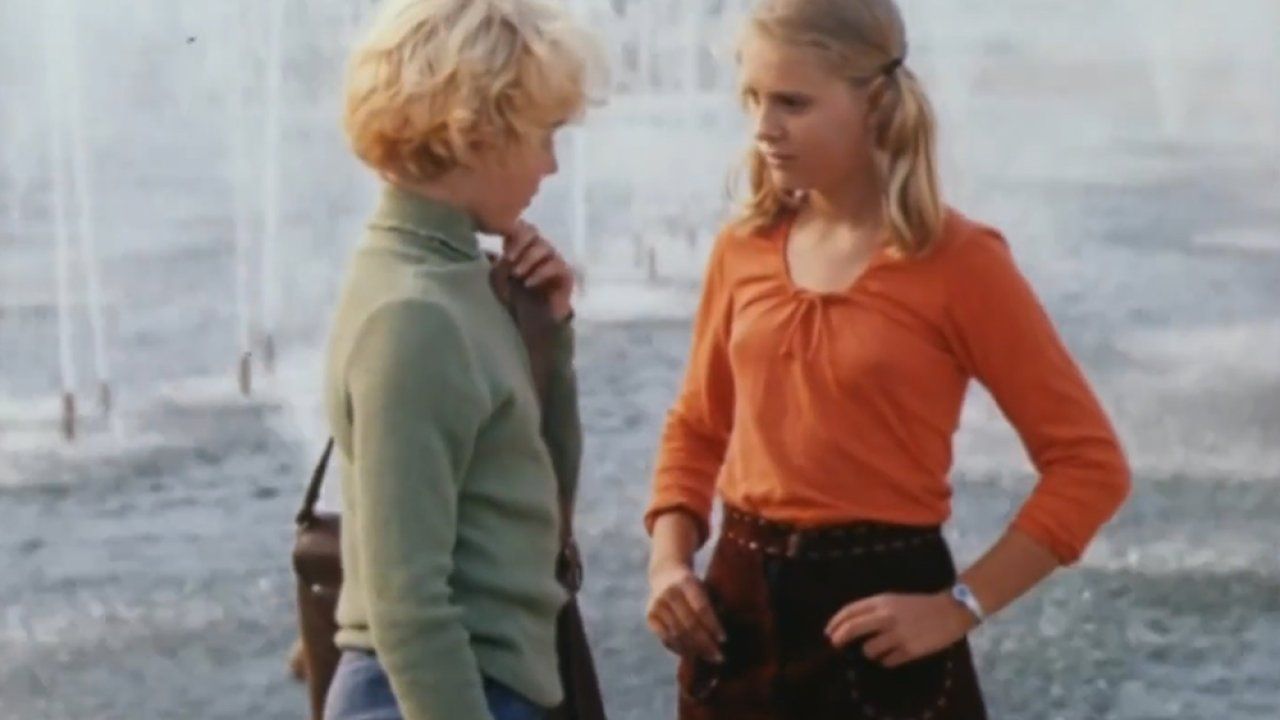 Две девушки разговаривают у фонтана на улице, стиль 80-х