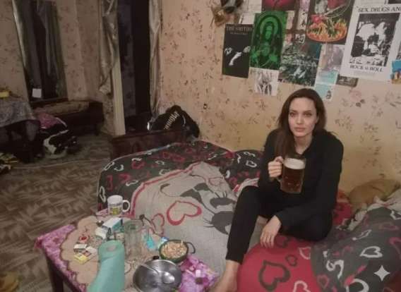 Девушка сидит на кровати в комнате, держит кружку пива.